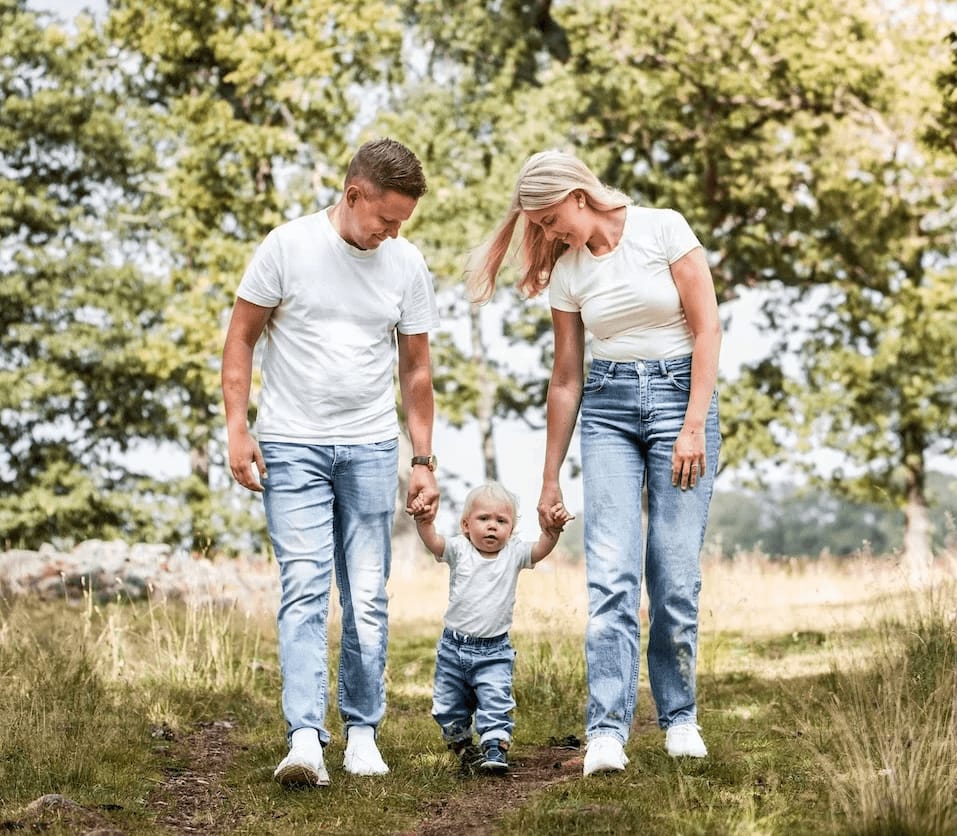 Familj går mot kameran med barnet emellan sig